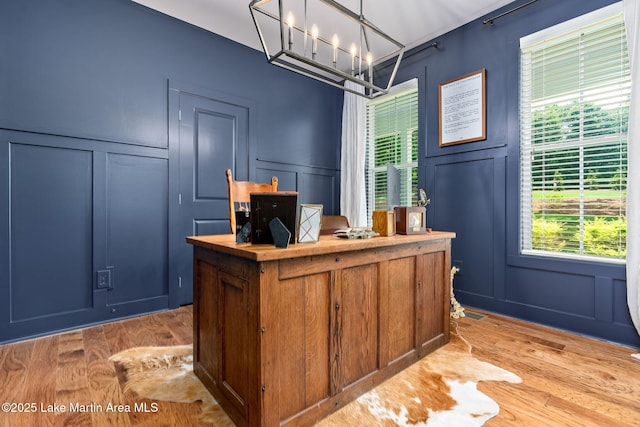 office featuring a healthy amount of sunlight, light wood-type flooring, and a notable chandelier