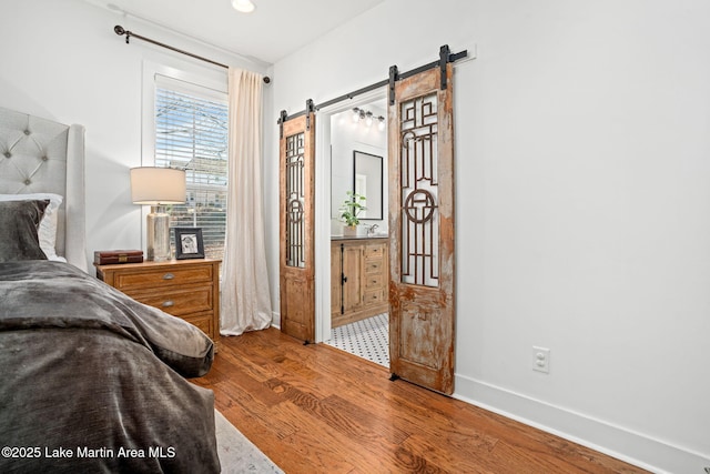 bedroom featuring a barn door and wood-type flooring