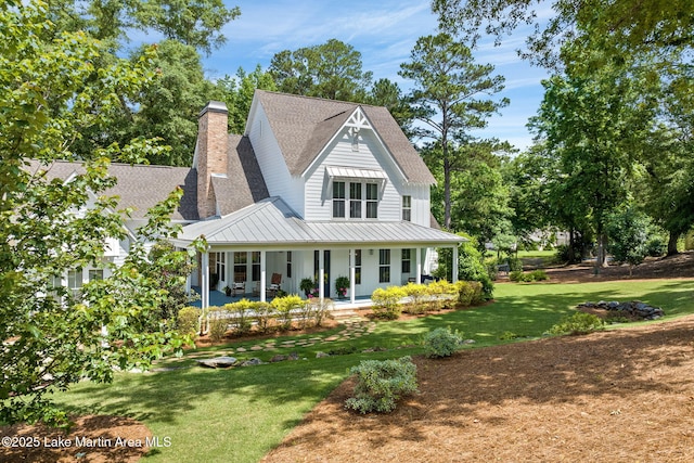 rear view of house featuring a lawn and covered porch