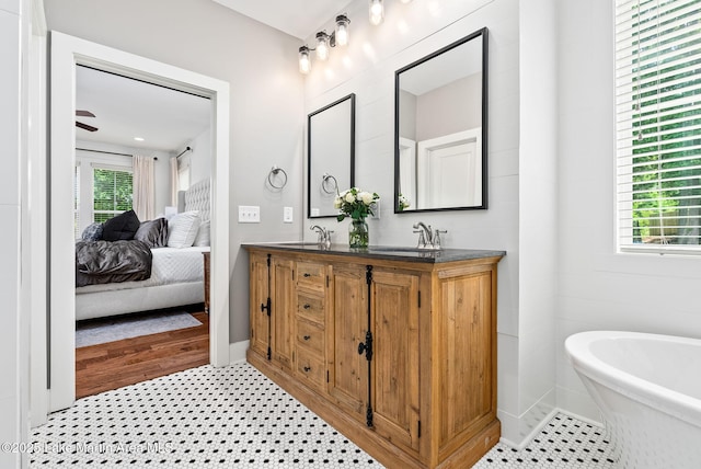 bathroom with tile patterned floors, ceiling fan, a tub to relax in, and vanity