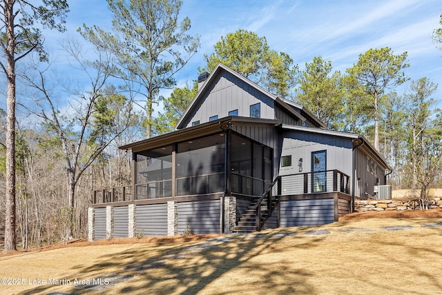 view of front of house featuring a sunroom, stairway, central air condition unit, and a chimney