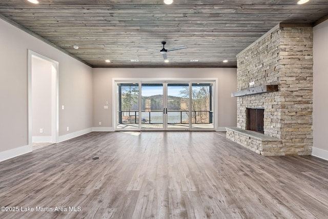 unfurnished living room featuring wood finished floors, baseboards, a stone fireplace, ceiling fan, and wooden ceiling