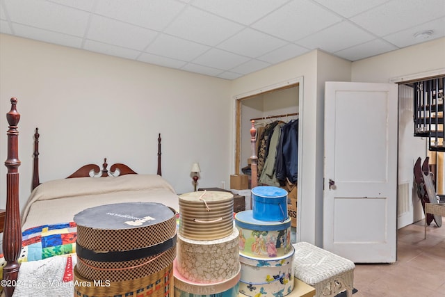 tiled bedroom with a paneled ceiling and a closet