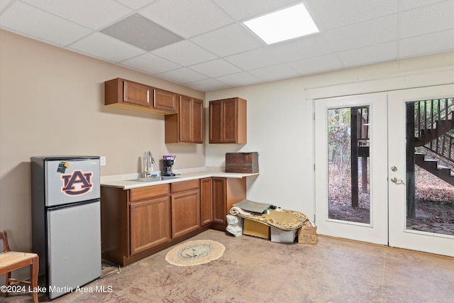 kitchen featuring stainless steel fridge, sink, a drop ceiling, and french doors