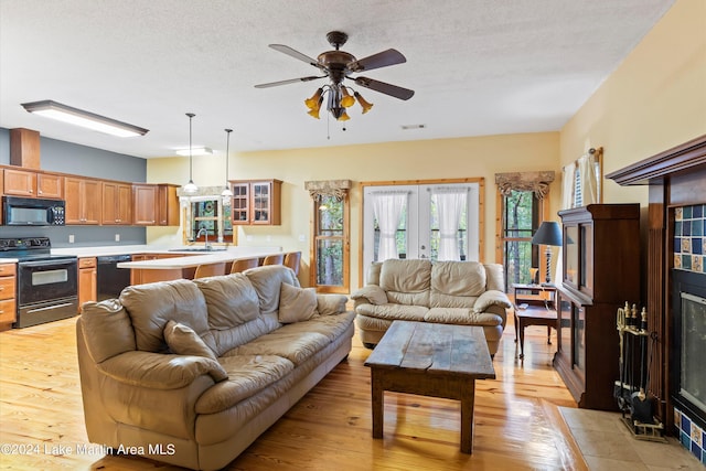 living room featuring french doors, light wood-type flooring, a textured ceiling, ceiling fan, and sink