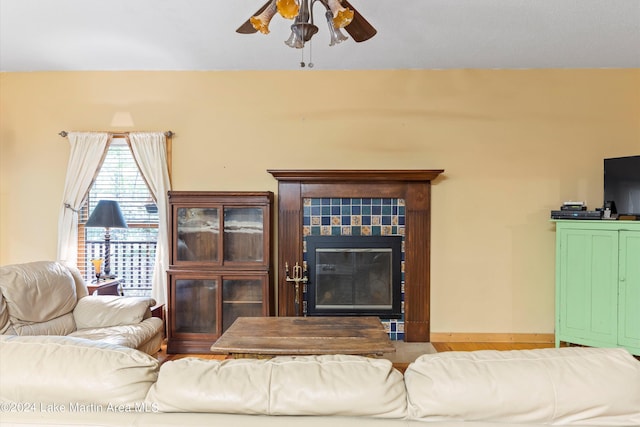 living room with ceiling fan and a tiled fireplace