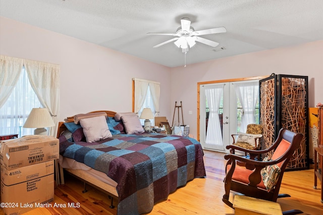 bedroom featuring access to exterior, light wood-type flooring, multiple windows, and ceiling fan