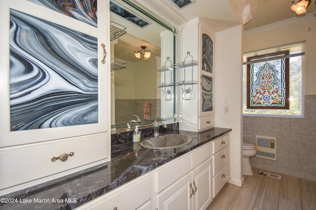 bathroom featuring hardwood / wood-style floors, vanity, toilet, ornamental molding, and tile walls