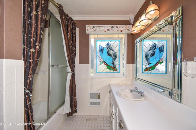 bathroom featuring vanity, combined bath / shower with glass door, crown molding, a textured ceiling, and tile walls