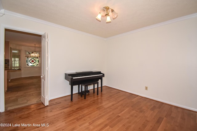 miscellaneous room with wood-type flooring, crown molding, and an inviting chandelier