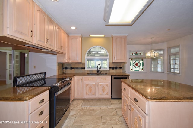 kitchen with appliances with stainless steel finishes, backsplash, sink, dark stone countertops, and a chandelier