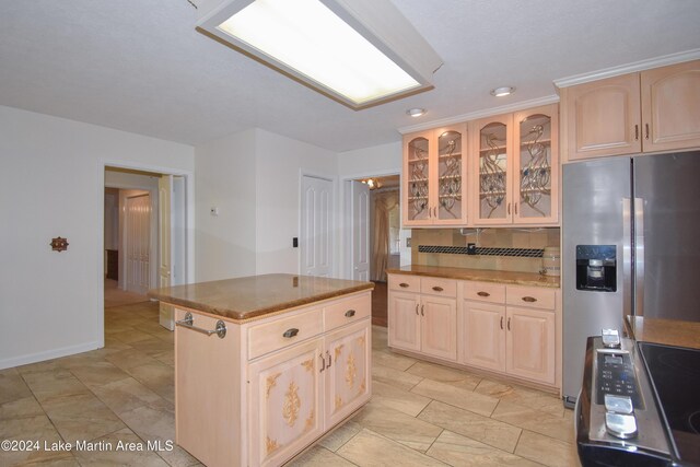 kitchen featuring tasteful backsplash, light brown cabinetry, a kitchen island, and stainless steel appliances