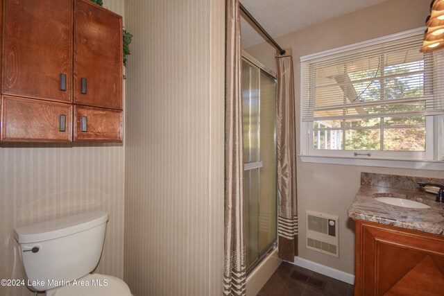 bathroom with a textured ceiling, vanity, toilet, and a shower with door