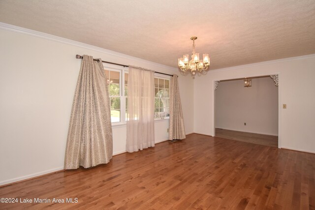 empty room featuring an inviting chandelier, wood-type flooring, a textured ceiling, and ornamental molding