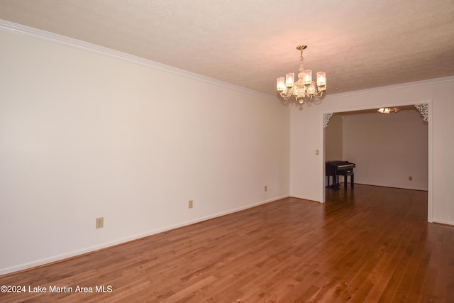 spare room with hardwood / wood-style flooring, ornamental molding, a textured ceiling, and an inviting chandelier