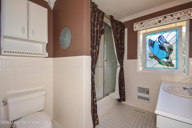 full bathroom featuring tile patterned floors, bath / shower combo with glass door, toilet, vanity, and tile walls