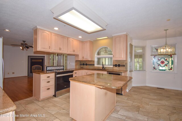 kitchen with a center island, stainless steel range with electric cooktop, ceiling fan with notable chandelier, sink, and decorative light fixtures