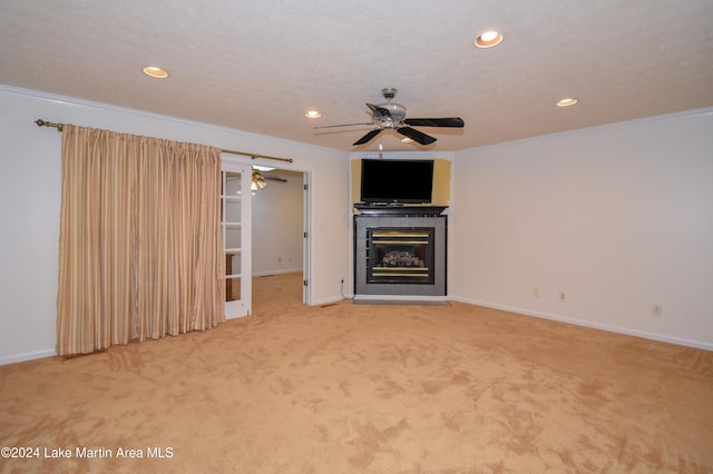 unfurnished living room featuring a tiled fireplace, crown molding, carpet floors, and a textured ceiling