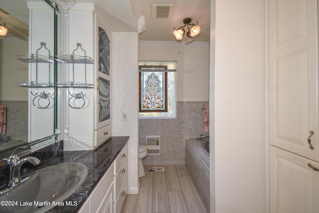 bathroom with vanity, toilet, ornamental molding, a tub to relax in, and tile walls