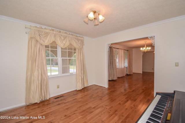 spare room featuring crown molding, hardwood / wood-style floors, and a chandelier