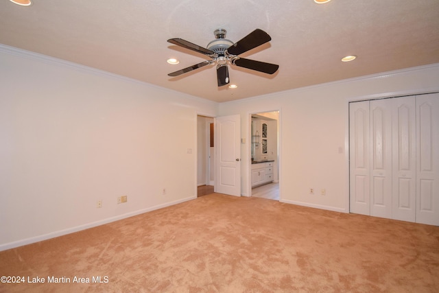 unfurnished bedroom with ceiling fan, crown molding, light carpet, and a closet