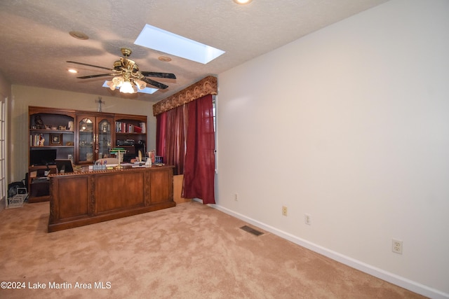 unfurnished office with a textured ceiling, light colored carpet, and ceiling fan