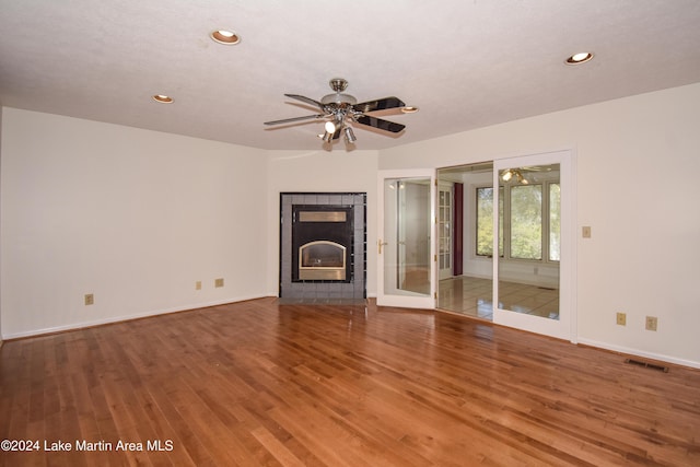 unfurnished living room with hardwood / wood-style floors, french doors, and a tiled fireplace