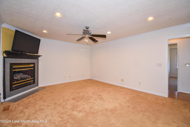 unfurnished living room featuring a tiled fireplace, crown molding, carpet floors, and a textured ceiling