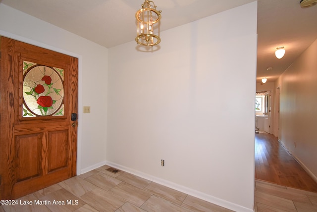 entryway with light wood-type flooring and an inviting chandelier