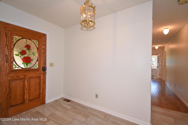 entryway with light wood-type flooring and an inviting chandelier