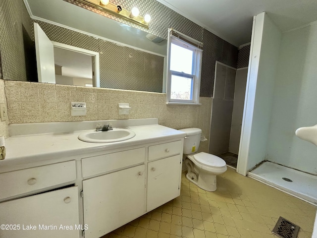 bathroom with tile walls, toilet, a shower, vanity, and crown molding