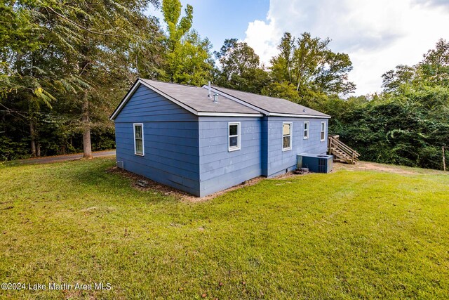 view of outdoor structure with central AC unit and a yard