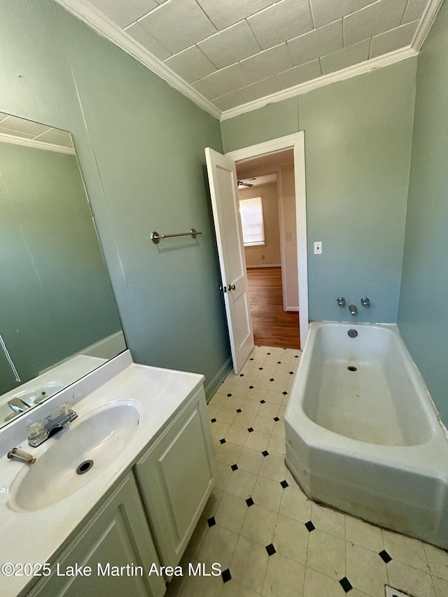 bathroom featuring a tub, ornamental molding, and vanity