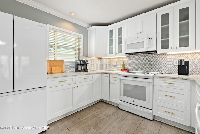 kitchen with white appliances, light stone countertops, ornamental molding, white cabinets, and tasteful backsplash