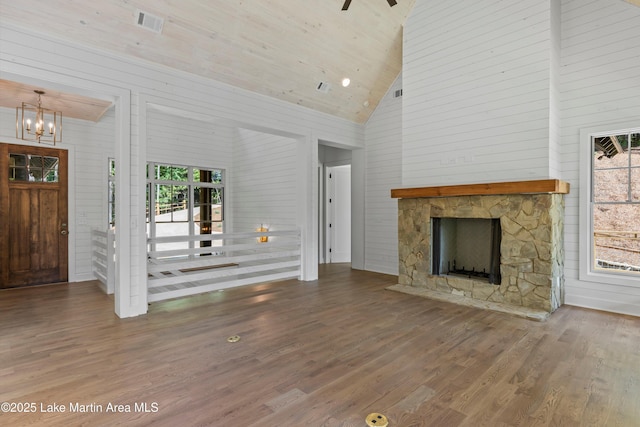 74 Cedar Rdg, Alexander City, AL 35010 - unfurnished living room with high vaulted ceiling, wood finished floors, a chandelier, a stone fireplace, and wooden walls