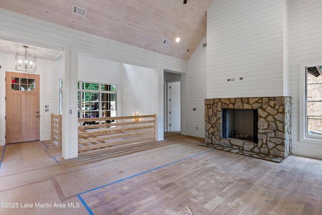 74 Cedar Rdg, Alexander City, AL 35010 - unfurnished living room featuring high vaulted ceiling, healthy amount of natural light, a chandelier, wood finished floors, and a stone fireplace