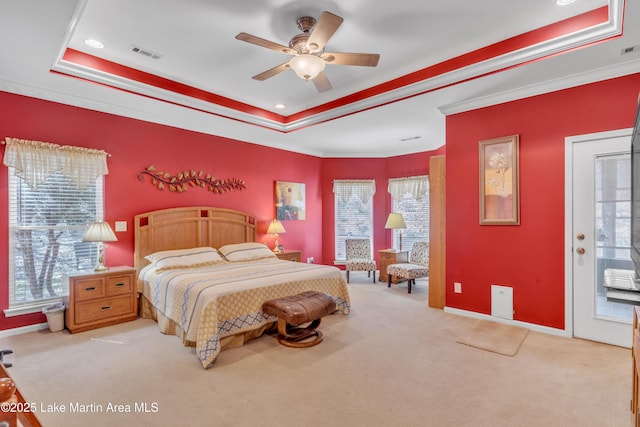 carpeted bedroom with visible vents, a raised ceiling, baseboards, and ornamental molding