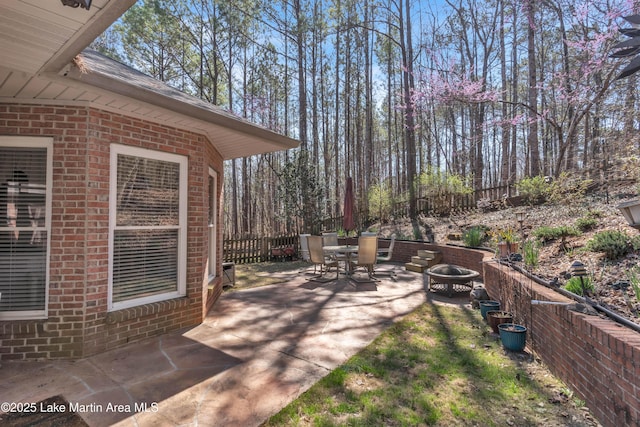 view of patio / terrace with a fire pit, outdoor dining space, and fence