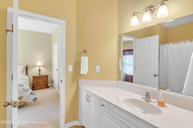 full bath with vanity, baseboards, and connected bathroom