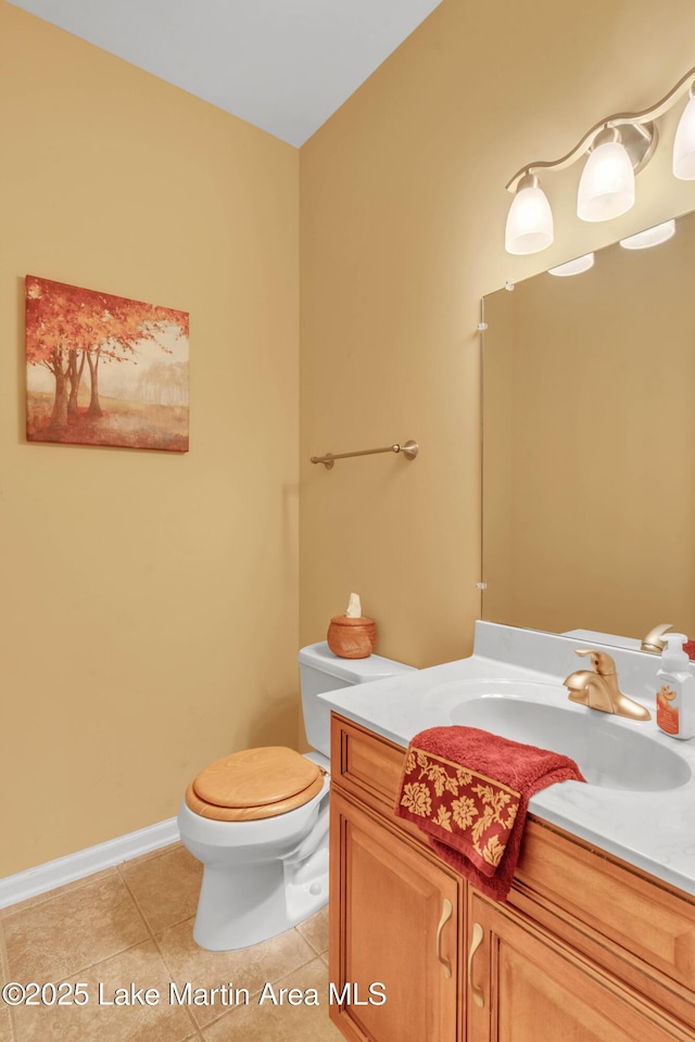 half bathroom with vanity, tile patterned floors, toilet, and baseboards