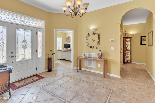 entrance foyer with light tile patterned floors, baseboards, arched walkways, and crown molding