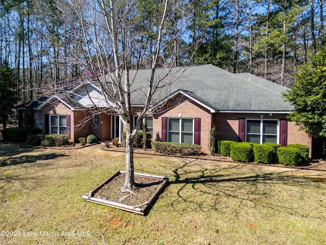 ranch-style house featuring a front lawn, brick siding, and roof with shingles