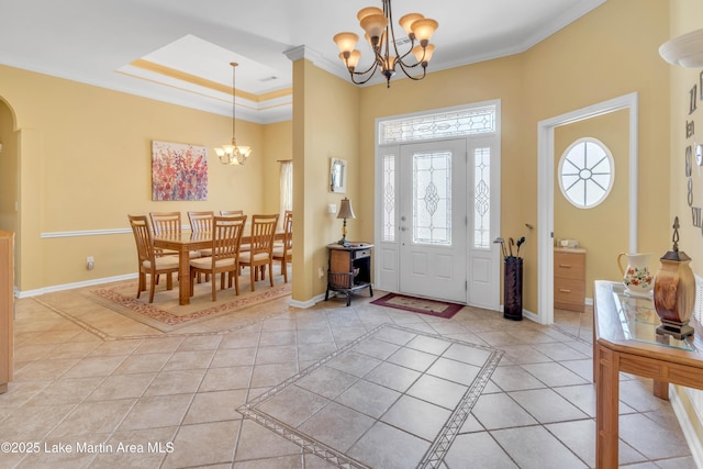 foyer with crown molding, baseboards, light tile patterned flooring, arched walkways, and a notable chandelier