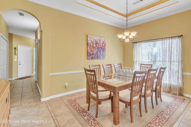 dining room with a tray ceiling, arched walkways, light tile patterned floors, baseboards, and a chandelier