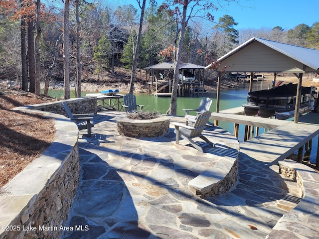 view of patio / terrace with a water view, an outdoor fire pit, and a dock