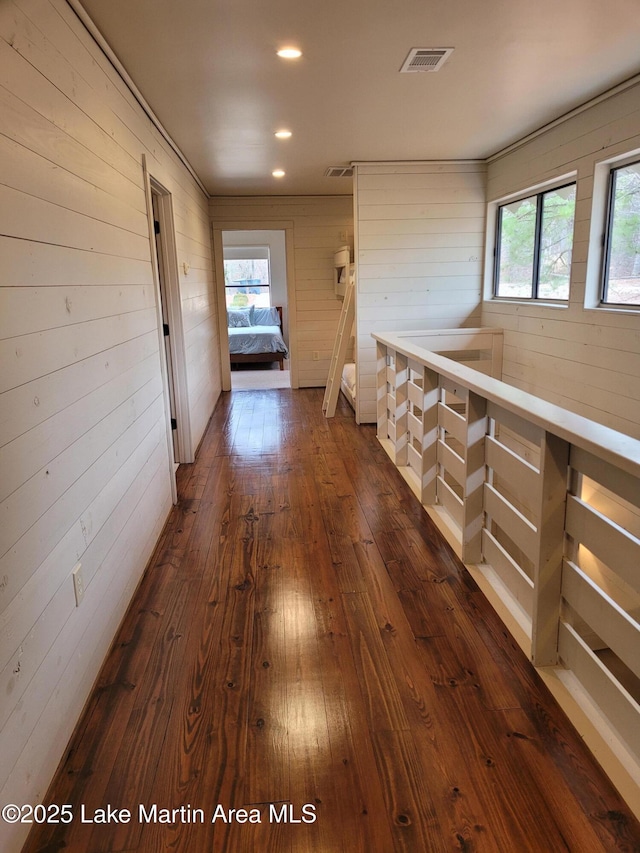 corridor with dark wood-type flooring and wooden walls