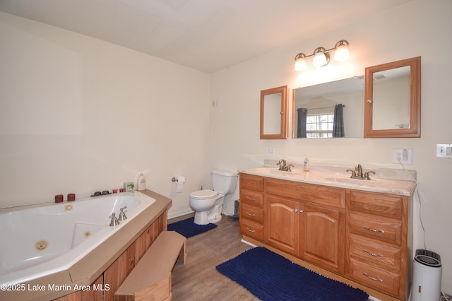 full bathroom with toilet, double vanity, a tub with jets, and a sink