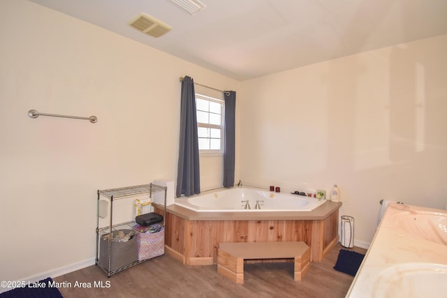 full bath featuring wood finished floors, visible vents, a sink, and a bath