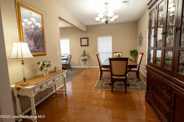 dining area featuring dark wood-type flooring and a chandelier