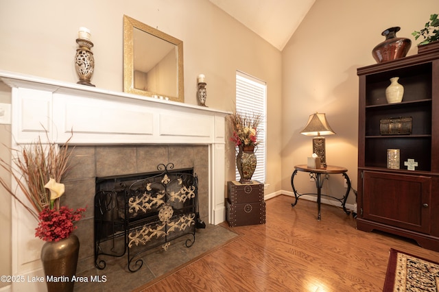 sitting room featuring lofted ceiling, a tiled fireplace, and hardwood / wood-style floors